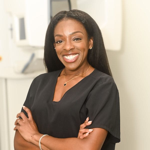 Dr. Ngozi Okoh smiling while wearing a pearl necklace and her dentist coat